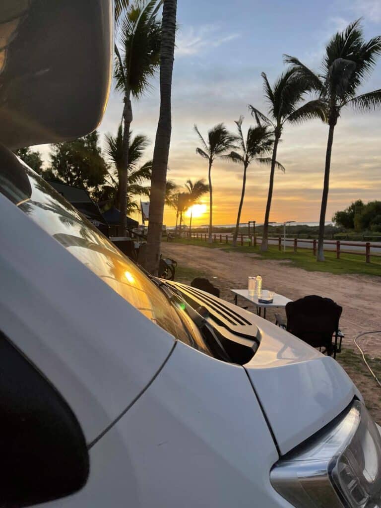 wohnmobil in australien im sonnenuntergang bei palmen