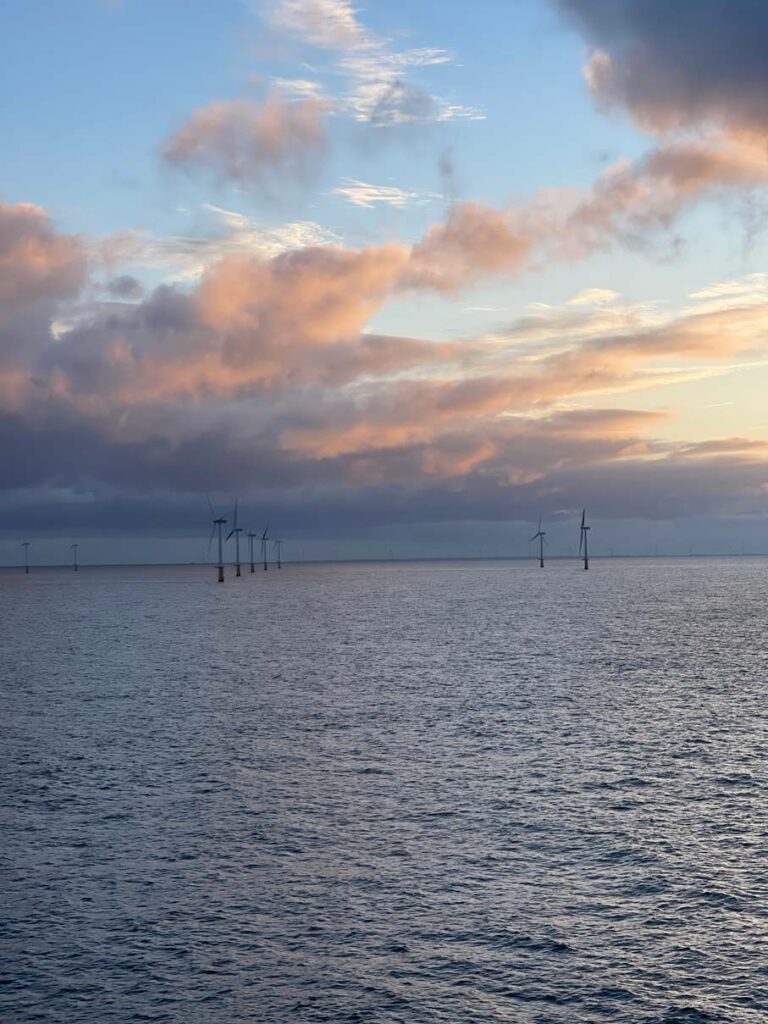 windräder im meer beim sonnenaufgang