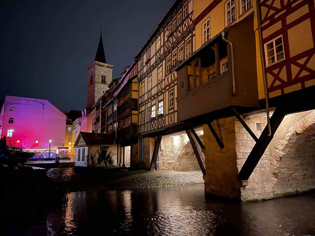blick auf die krämerbrücke im dunkeln vom flussufer