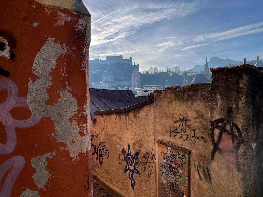 gasse mit graffiti dahinter blick auf festung hohensalzburg