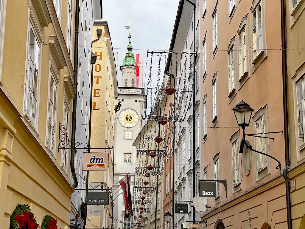 blick durch die gebäude der getreidegasse auf kirchturm in salzburg