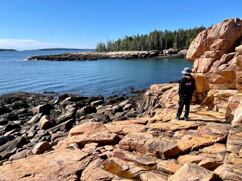 kind steht am ufer im acadia nationalpark auf felsküste