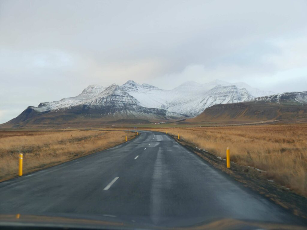 straße auf island führt auf schneebedeckten berg zu