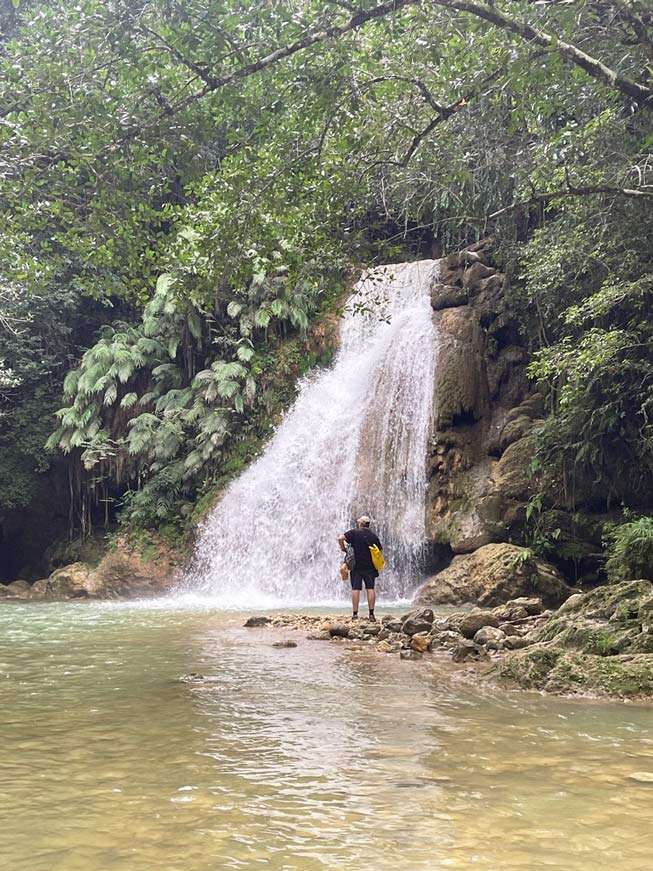 mann steht vor Wasserfall in der Dom Rep