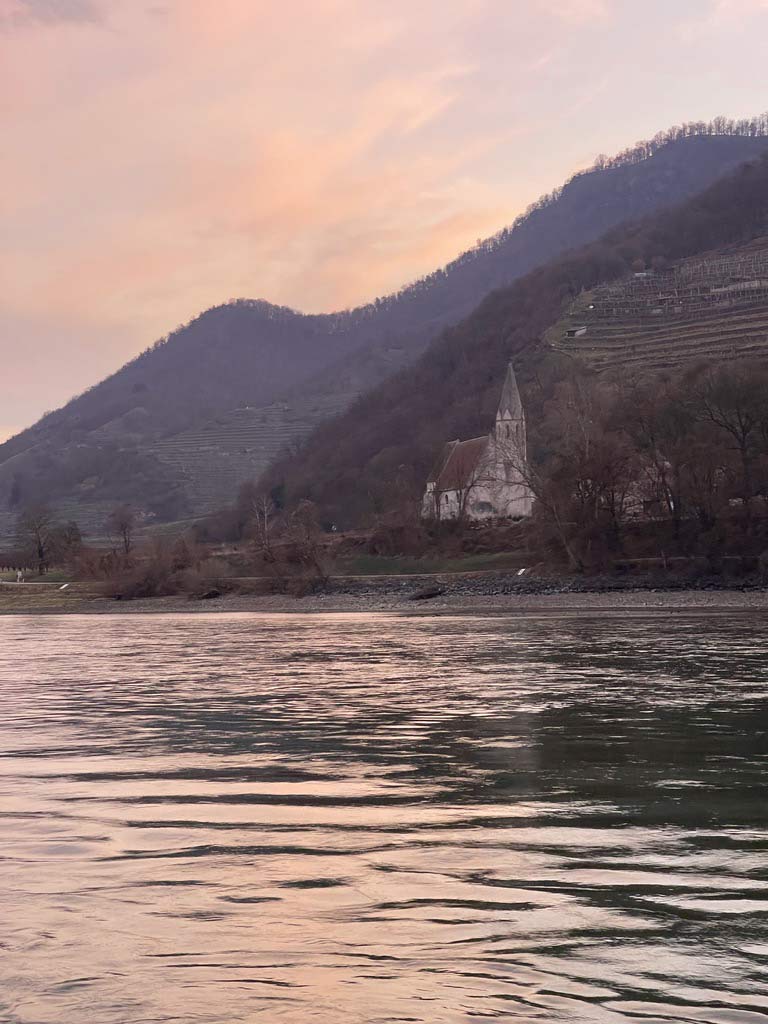 kirche am flussufer der donau im sonnenaufgang