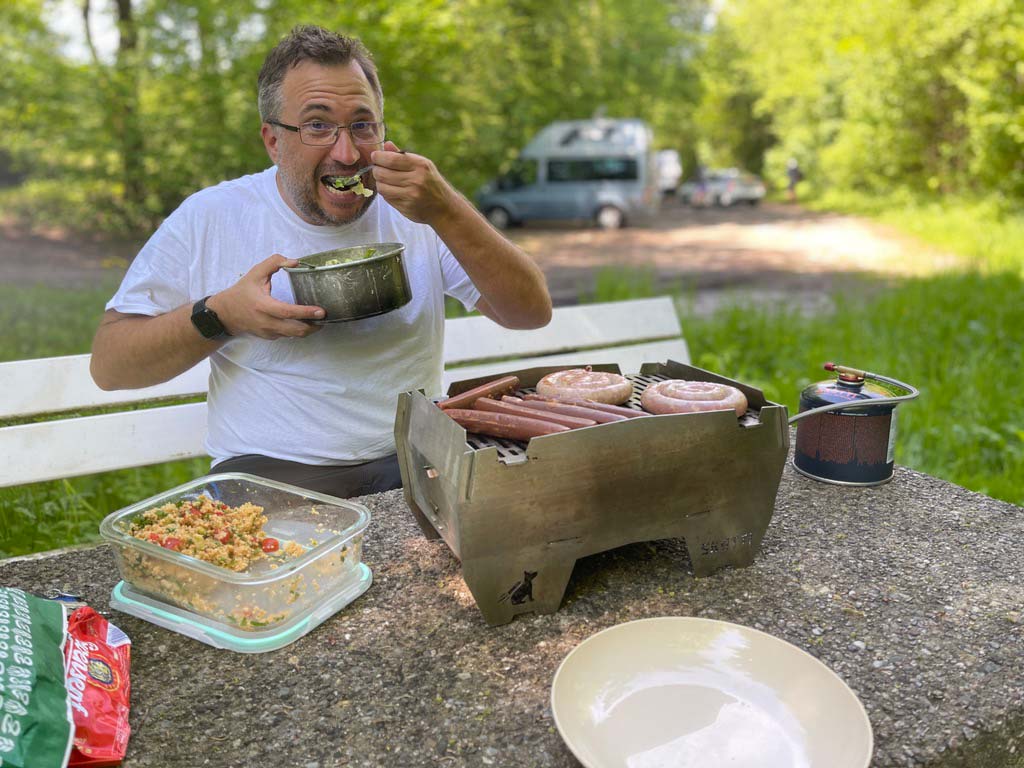 mann grillt auf camping grill an rastplatz